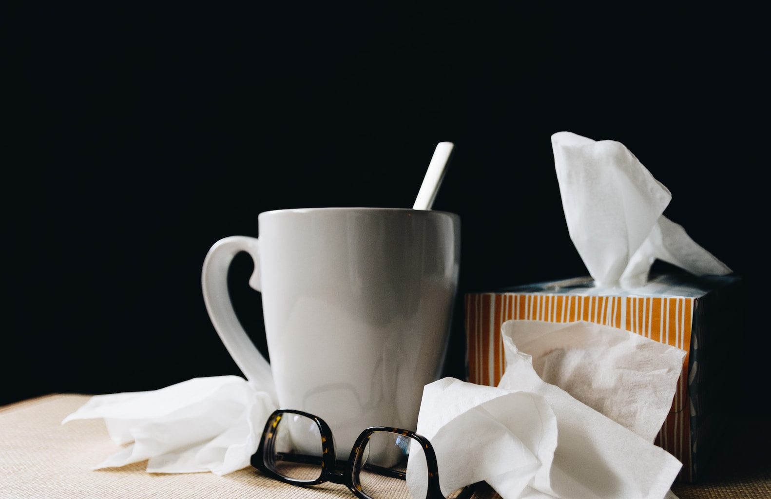 white ceramic mug on white table beside black eyeglasses