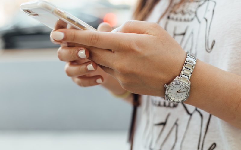 woman holding iPhone during daytime