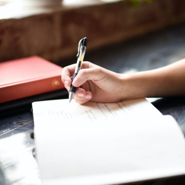 a person writing on a piece of paper with a pen