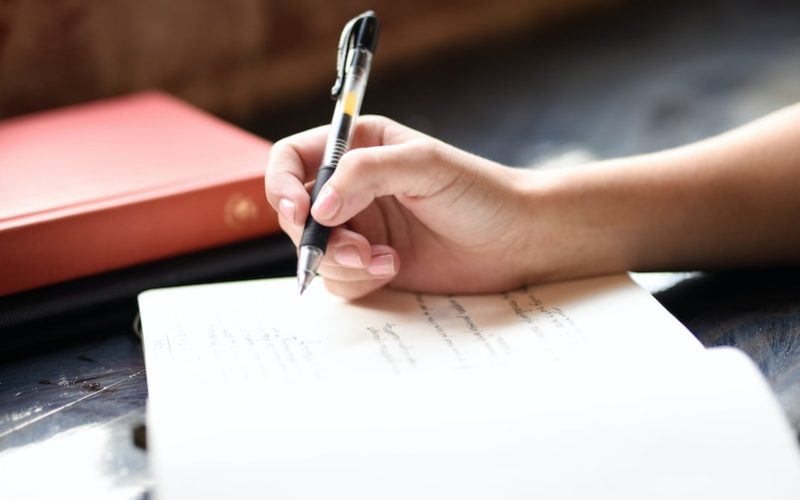 a person writing on a piece of paper with a pen