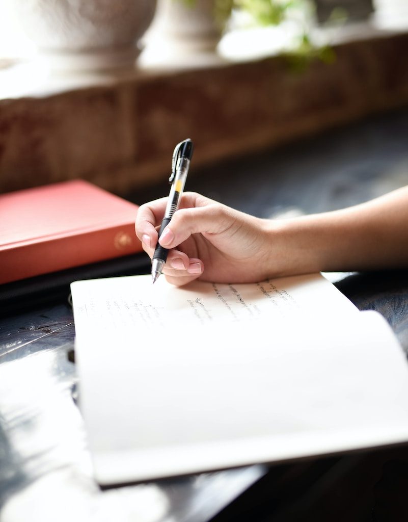 a person writing on a piece of paper with a pen