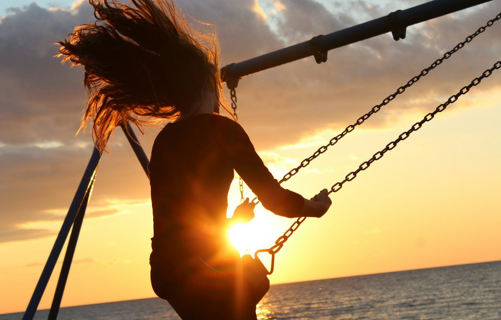 woman riding on swing during sunset