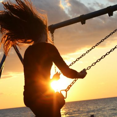 woman riding on swing during sunset