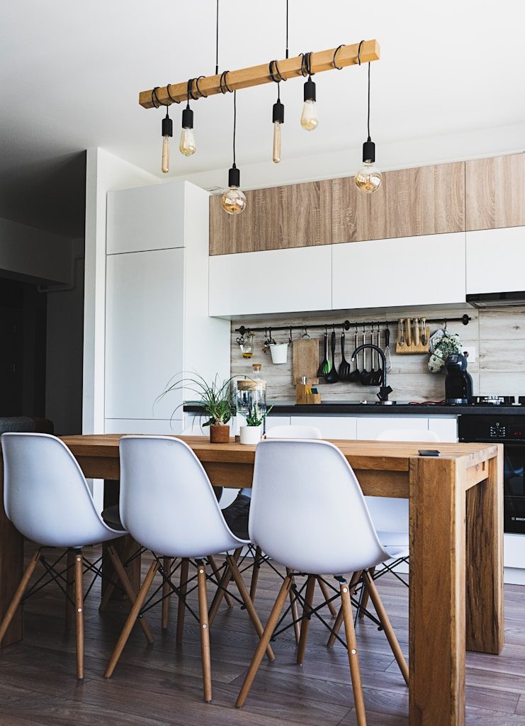 brown wooden dining table with white chairs near kitchen