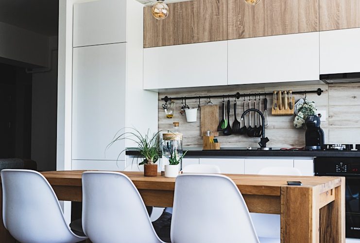 brown wooden dining table with white chairs near kitchen