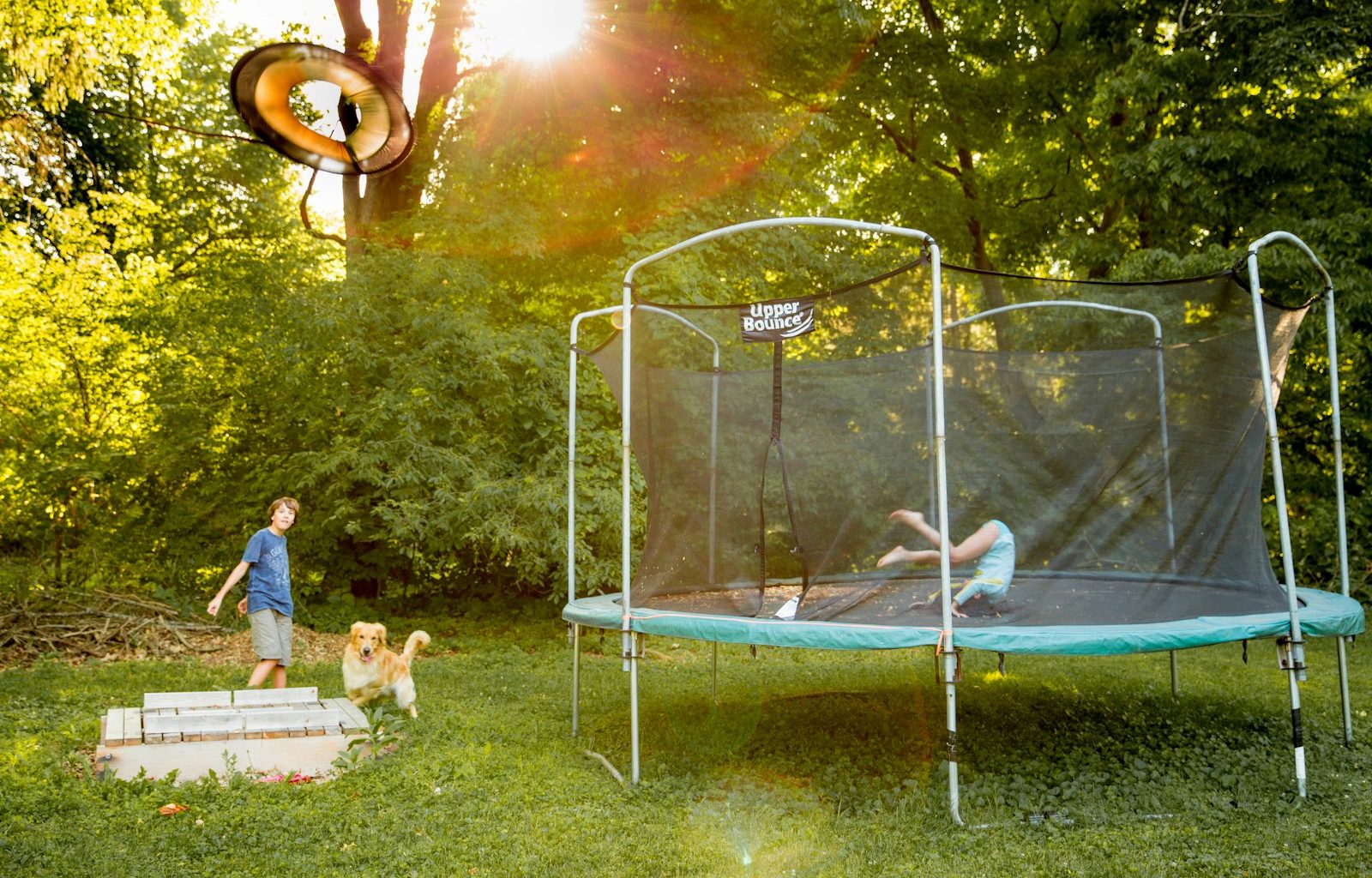 two children playing on a trampoline in a yard