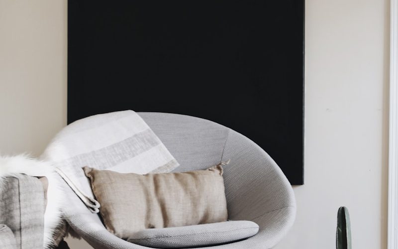 round grey moon chair with brown pillow on top