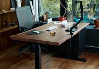 a desk with a laptop on it in front of a window