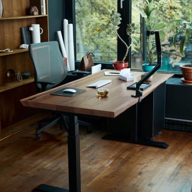 a desk with a laptop on it in front of a window