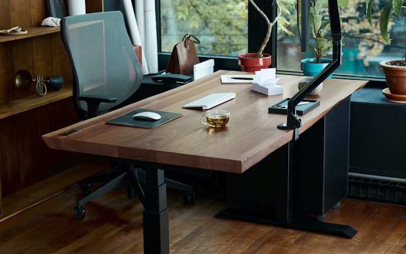 a desk with a laptop on it in front of a window