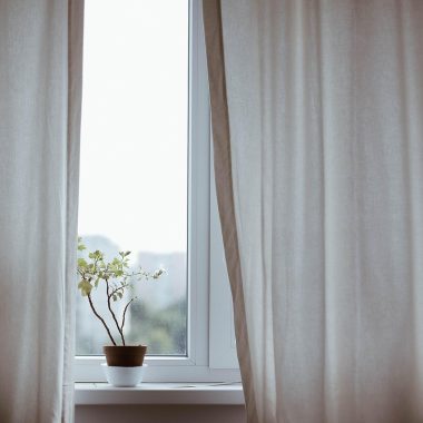 Gordijnen netjes opgehangen voor een raam in een lichte woonkamer