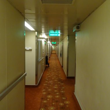 Smalle gang met netjes opgeborgen schoenen op een smal rek naast de voordeur