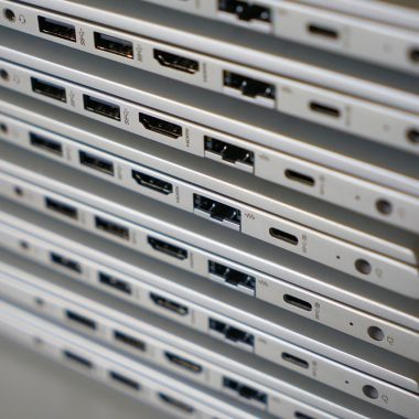 Iemand maakt een USB-C oplaadpoort schoon met een tandenstoker en perslucht