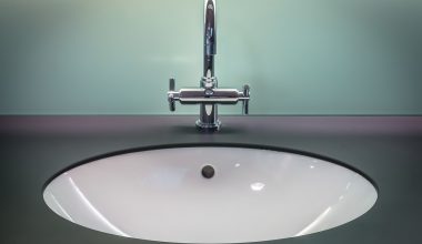 Chromen kraan in badkamer met witte kalkaanslag die wordt schoongemaakt